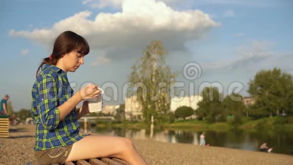 女孩在河岸的鹅卵石海滩上吃热面视频的预览图