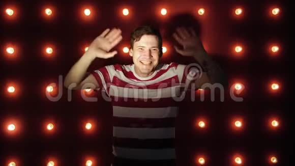 一个快乐的年轻人站在红色背景上挥舞着手的肖像视频的预览图