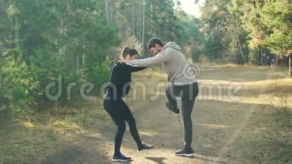 男人和女人正在公园里享受运动互相抱着对方肩膀和活动腿热身关节站在上面视频的预览图