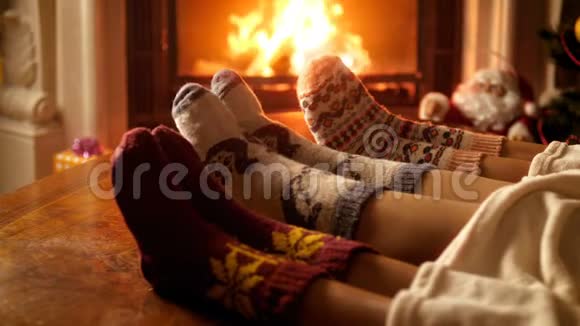 圣诞前夜一家人穿着温暖的羊毛袜子在燃烧的壁炉旁警告使人放松视频的预览图