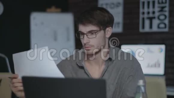体贴的商人在黑暗的办公室里用电脑处理文件视频的预览图