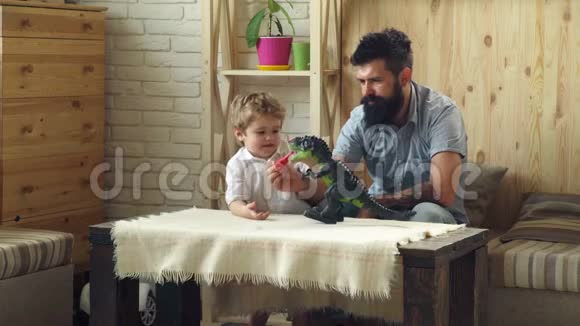 可爱的小孩和长胡子的父亲玩塑料恐龙儿子和父亲之间的战斗视频的预览图