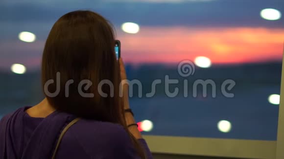 快乐的女人在手机上慢镜头地通过机场窗口拍照视频的预览图