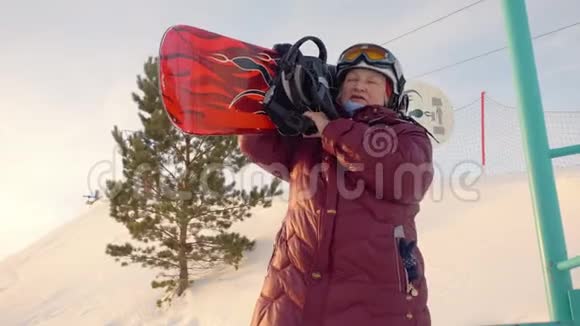 一位年长的妇女在雪山上肩上扛着滑雪板视频的预览图