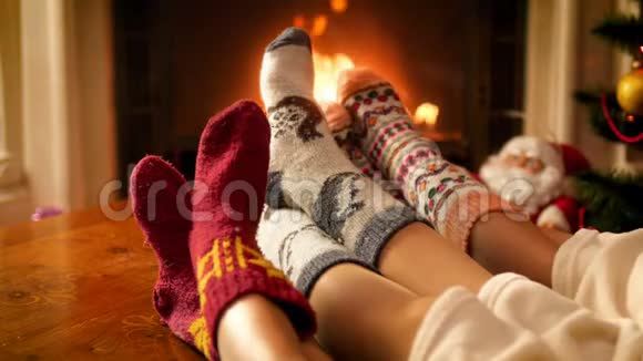 4k视频父母带着孩子穿着温暖的羊毛袜子躺在毯子下在燃烧的壁炉里取暖视频的预览图