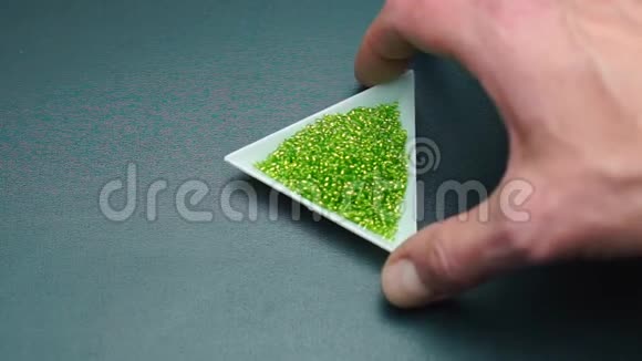 一只手的特写旋转着一个带绿色珠子的三角形盘子视频的预览图