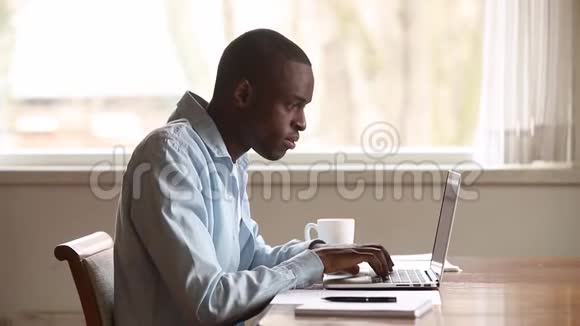 沮丧沮丧的黑人使用笔记本电脑在线阅读坏消息视频的预览图