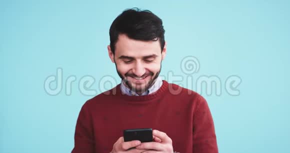 在镜头前一个快乐而有魅力的男人用他的智能手机在录音室里用一个视频的预览图