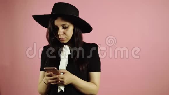 令人震惊的快乐黑发随机女人使用智能手机粉红色背景视频的预览图