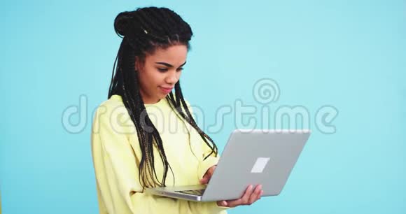 在一个蓝底墙的工作室里一位非洲女士在笔记本上打字或在网上搜索她是视频的预览图