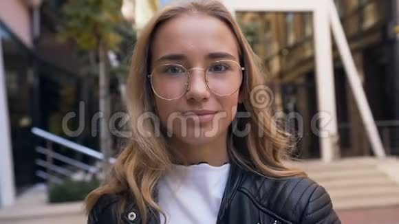 特写一幅可爱的白种人女人的肖像她戴着眼镜在街边的镜头上微笑着视频的预览图
