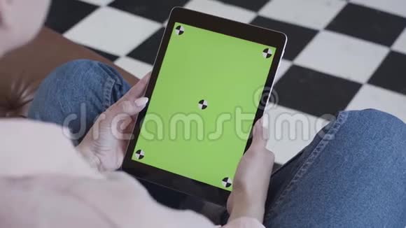 年轻的黑发女人看着她的平板电脑绿色屏幕在黑白地板背景库存录像侧视图视频的预览图