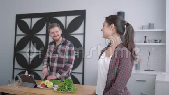 厨房里的快乐女性画像微笑的女性看着从蔬菜中准备健康有用的食物的男性视频的预览图