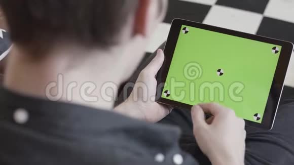 技术和互联网概念在肩膀上看到一个男人敲击着一块追踪平板电脑的绿色屏幕视频的预览图