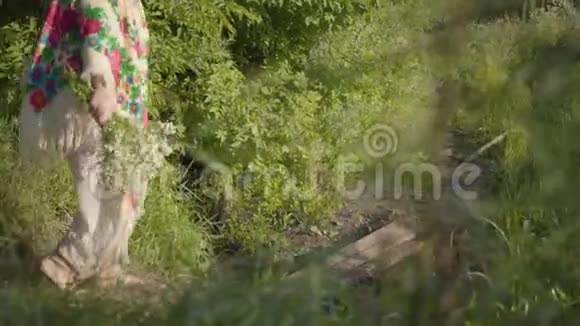 美丽的超重女人头上戴着花环手里拿着鲜花穿过小桥视频的预览图