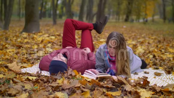 约会的情侣在秋天的大自然中读书视频的预览图