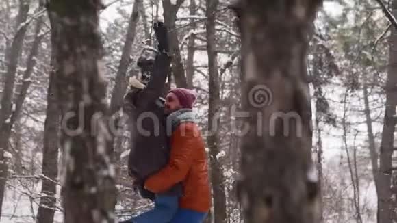 男人旋转或旋转快乐的女朋友牵着她在松林下的雪有爱的夫妻玩得开心视频的预览图