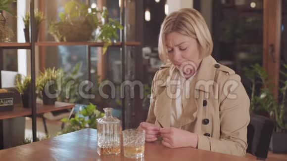 孤独悲伤的金发女人在酒吧喝酒视频的预览图