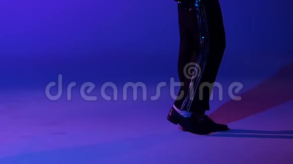年轻时尚的男子舞蹈风格迈克尔杰克逊聚光灯在蓝色背景双腿并拢动作缓慢视频的预览图