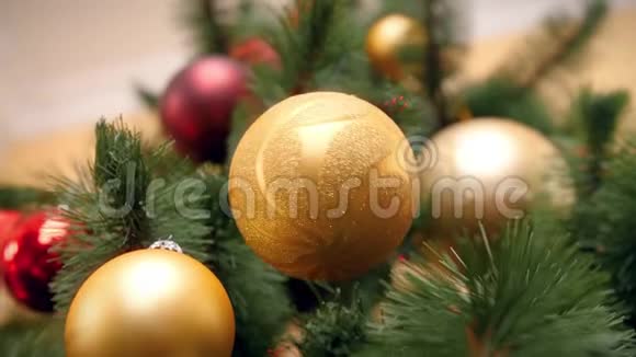 在客厅的圣诞树树枝上悬挂和旋转美丽的金色泡泡的4k镜头视频的预览图