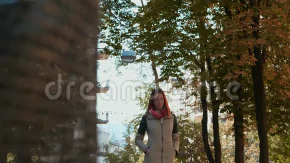 穿着夹克的年轻红头发女人正在公园里散步视频的预览图