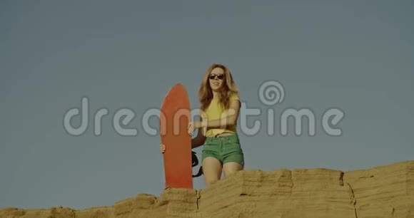 沙漠里有沙板的性感女孩体育旅游生活方式商业广告概念拍摄于4k红色视频的预览图