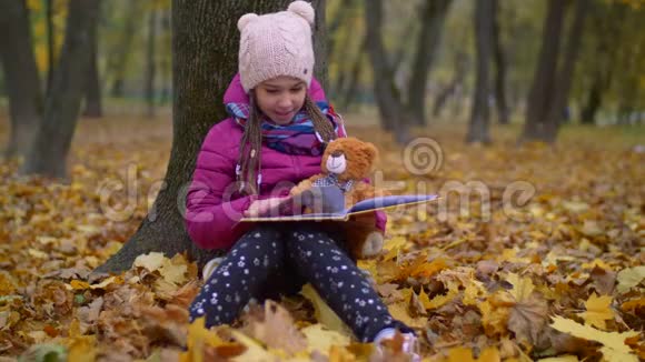 秋天公园树下可爱的女孩看书视频的预览图