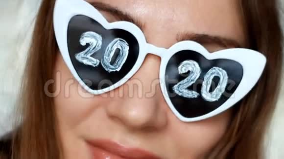 肖像特写女士戴太阳镜数字2020新年圣诞节女孩微笑着看着摄像机视频的预览图