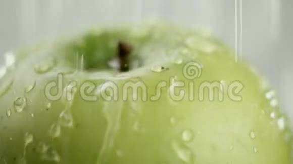 在视频中我们看到一个绿色的苹果水从顶部涌出白色背景特写视频的预览图