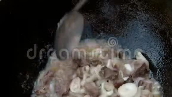 洋葱的肉用黑色的铸铁锅炒厨师用勺子把原料混合然后把开水倒在上面视频的预览图