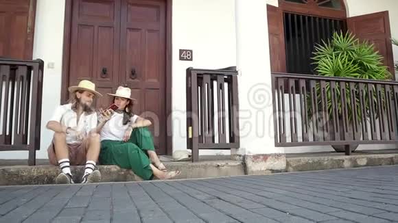 年轻时尚的夫妇戴着草帽坐在门口视频的预览图
