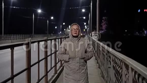 晚上的女孩在城里走来走去那个女孩在桥上照相机从前面拍动回放缓慢视频的预览图