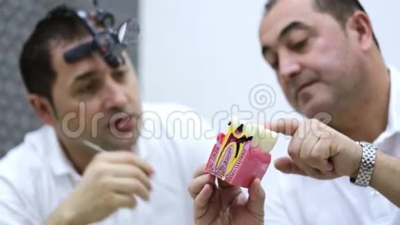 牙齿矫正师和牙医在使用牙齿模型时讨论治疗方案视频的预览图