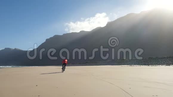 年轻人骑着自行车在加那利群岛的沙滩上朝大西洋的海浪走去兰萨罗特视频的预览图