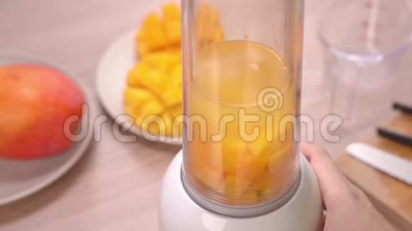 在明亮的木桌背景下在夏季厨房中新鲜制作芒果汁健康女性自制概念慢动作视频的预览图
