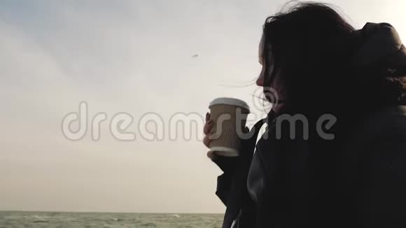 女孩在海天相接的背景下用一次性杯子喝一杯视频的预览图