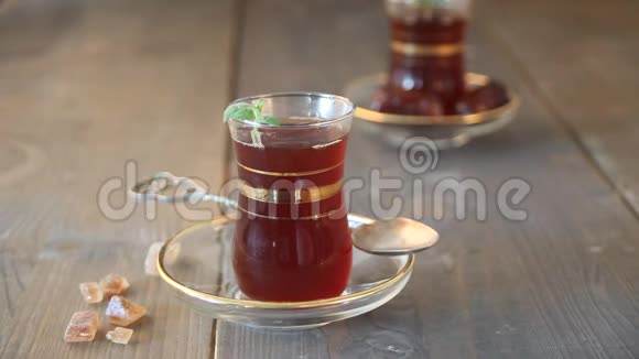 女人的手传统的玻璃杯里放着一个盘子放在木桌上放着土耳其茶东方人视频的预览图