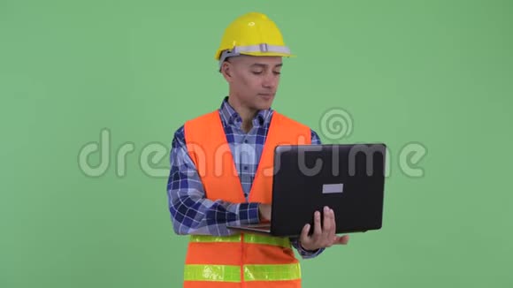 快乐的多民族建筑工人思考使用笔记本电脑视频的预览图