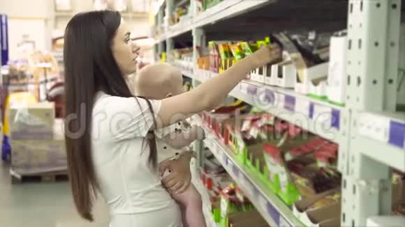 漂亮的女人带着小儿子在超市购物年轻的母亲在市场上为家人选择香料视频的预览图