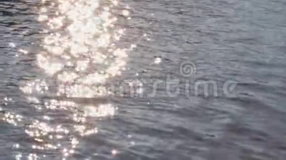 平静的蓝色波浪在海洋或河流中金色耀眼的阳光和水面上的涟漪摘要bokeh背景视频的预览图