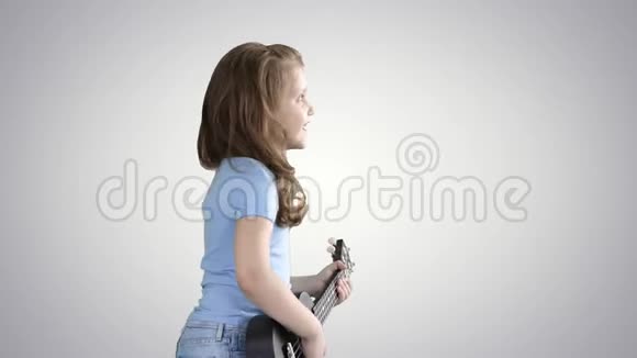 可爱的小女孩走路和唱歌同时在四弦琴上演奏梯度背景视频的预览图
