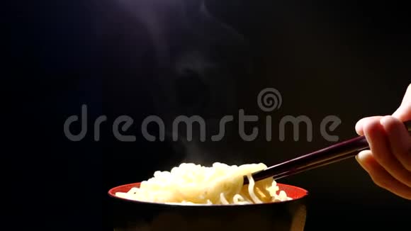 筷子到美味的面条蒸汽和烟雾在碗的黑色背景下缓慢运动亚洲餐特写垃圾食品和FA视频的预览图