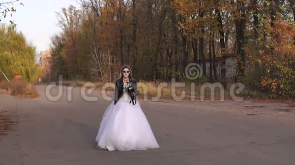 一个年轻的女孩在一条空荡荡的路上用头骨的形式做着令人毛骨悚然的化妆视频的预览图