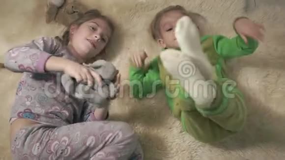 可爱的小孩子穿着睡衣在地板上滚动与蓬松的地毯兄弟姐妹玩得开心孩子们周末快乐视频的预览图