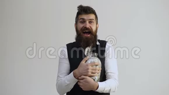 商钱人和财经新闻理念留着胡子的人拿着一个装满钱的罐子被孤立在白色背景上视频的预览图