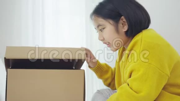 可爱的亚洲女孩在纸箱里玩捉迷藏的慢动作视频的预览图