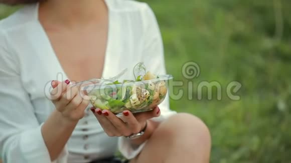 坐在草地上吃沙拉的美女视频的预览图
