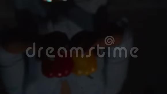 两个多汁的成熟甜椒在一个年轻的女人手中的黑色背景视频的预览图