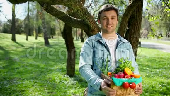 一个快乐的年轻农民把新鲜蔬菜放在篮子里的肖像关于自然的背景视频的预览图