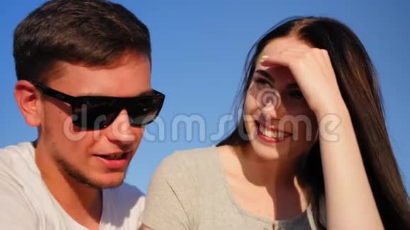 年轻幸福夫妇的肖像浪漫的夫妇坐在蓝天上一起快乐近距离射击视频的预览图
